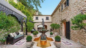 Ein Innenhof mit Brunnen, Bank und Blumentöpfen.