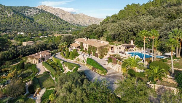 Eine Villa im mediterranen Stil mit Swimmingpool, umgeben von üppigen Gärten und Bergen.