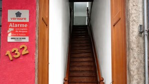 A staircase leading to a room with a red wall and a sign indicating a security alarm system. - Hospedagem Rio Lapa  (Rio de Janeiro)