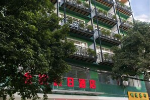 Een hotel met meerdere verdiepingen, balkons en een groene gevel.