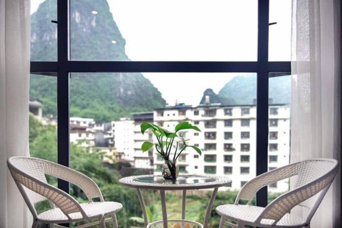 Una habitación con vistas a montañas y edificios, que incluye una mesa redonda con sillas y un jarrón con una planta.