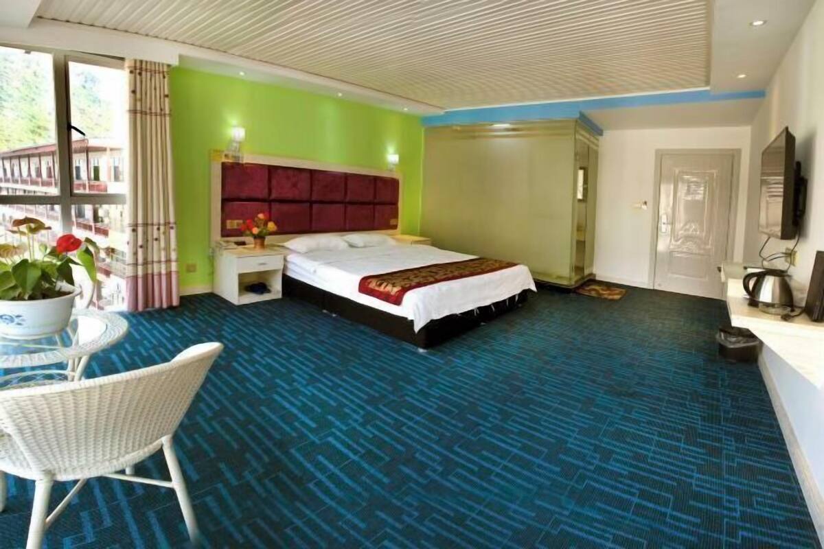 Una habitación de hotel con una cama grande, una mesita de noche, una silla y una ventana con cortinas.