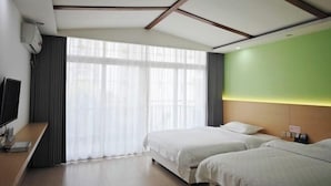 Ein Hotelzimmer mit großem Fenster, Flachbildfernseher, Schreibtisch aus Holz und zwei Betten.