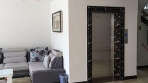 Eine moderne Lobby mit einer Couch, einem gerahmten Bild an der Wand und einem Marmor-Aufzug.