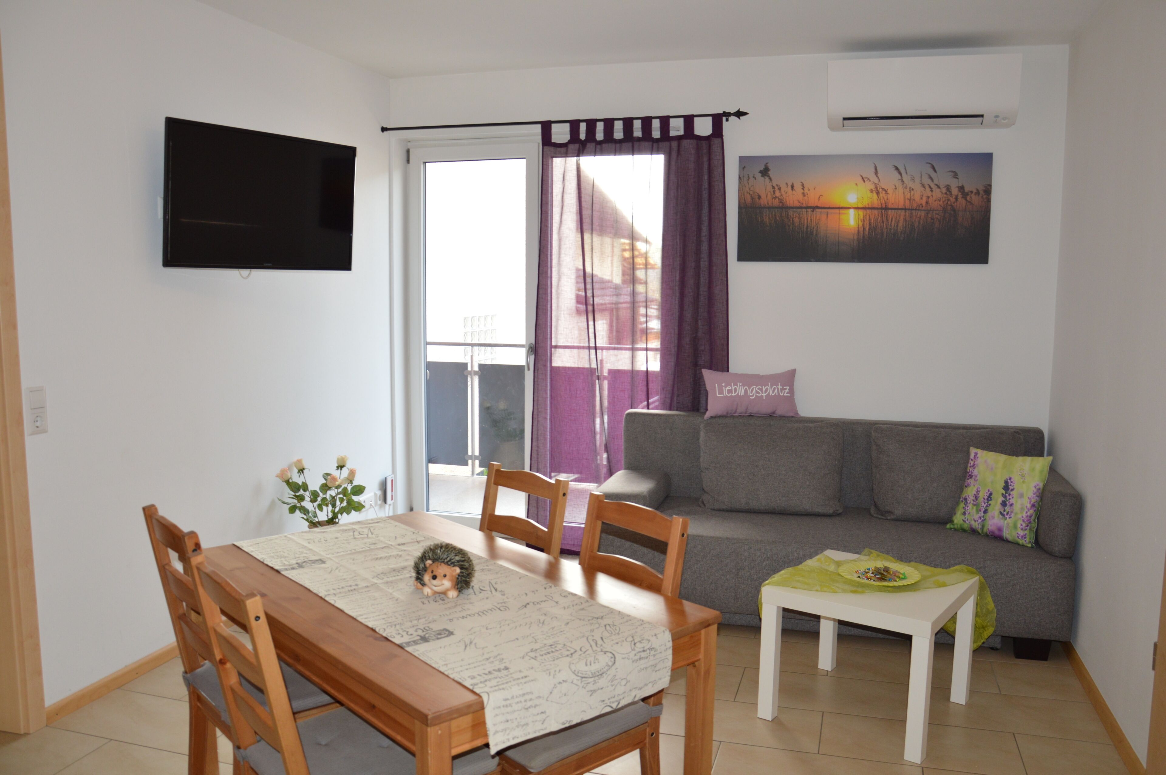 Un salon avec un téléviseur, un canapé et une table à manger avec des chaises.