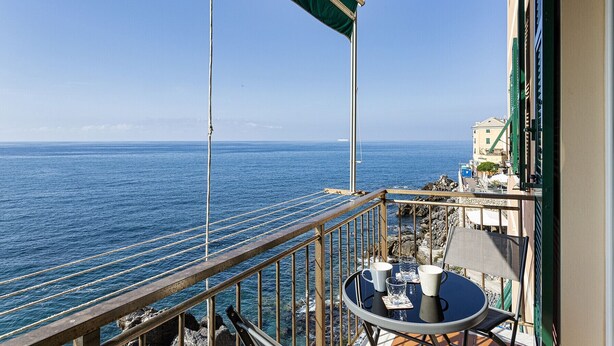 Un balcon avec une table, des chaises et une vue sur la mer et un navire au loin.