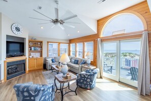 Un salon spacieux avec une cheminée, un téléviseur et un balcon offrant une vue agréable.