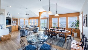 A spacious living area with a dining table, chairs, and a sofa. - Magnificent oceanfront home in South Nags Head! (South Nags Head)