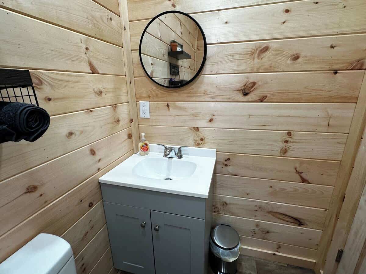 Een kleine badkamer met een wit wastafelmeubel, een spiegel en een toilet.
