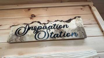Ein Holzschild mit dem Schriftzug 'Inspiration Station' an einer Holzwand.