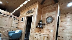 A wooden cabin interior with a blue armchair, a wooden cabinet, and a 'hello' sign. - Inspiration Station (Pikeville)