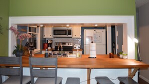 A modern kitchen with a wooden table and chairs, a microwave, oven, and a refrigerator. - Cozy Winston-Salem Vacation Cabin (Winston-Salem)