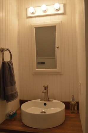 Ein Badezimmer mit einem runden Waschbecken, einem Spiegel und einem Handtuchhalter.