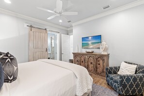 A bedroom with a bed, a wooden cabinet, a sofa, a ceiling fan, and a painting on the wall. - Close to Seaside ~ Fully Stocked Kitchen ~ Golf Cart ~ Two Community Pools (Santa Rosa Beach)