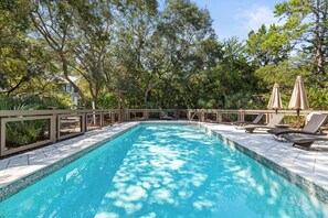 A rectangular swimming pool with tiled edges, surrounded by lounge chairs and umbrellas, set in a landscaped garden with trees and a pergola. - Close to Seaside ~ Fully Stocked Kitchen ~ Golf Cart ~ Two Community Pools (Santa Rosa Beach)