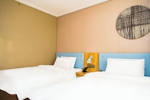 A hotel room with two beds, a wooden nightstand, a lamp, and a wall-mounted artwork.