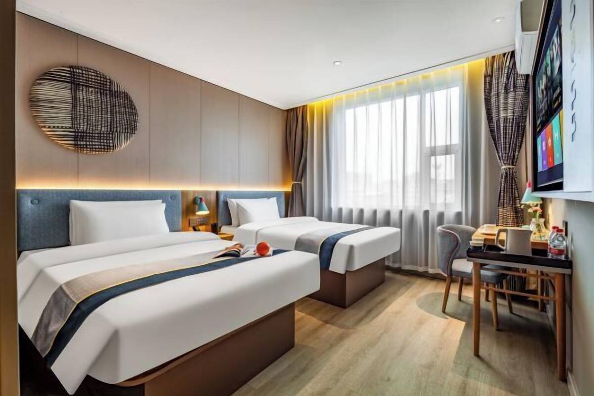 A hotel room with two beds, a desk, and a chair.