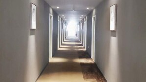 A long, narrow hallway with a series of doors on one side and framed pictures on the other. - Homeinn · neo (Changzhi Medical College) (Changzhi)