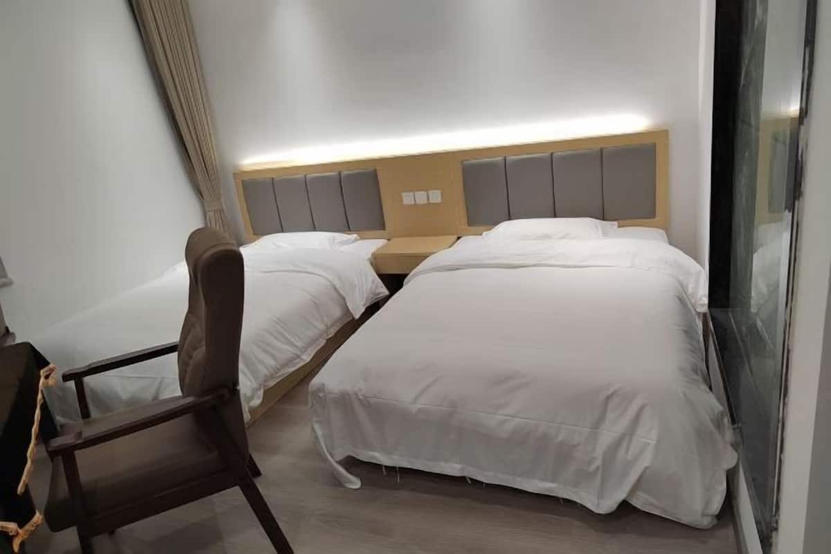 A hotel room with two beds, a desk, and a chair.