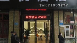A hotel entrance with a modern design, featuring a reception desk and seating area inside. - Xingyue Hotel (Chongqing)