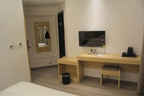 A hotel room with a wooden desk, a television, a small trash bin, and a single chair. - Xingyue Hotel (Chongqing)
