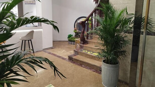 A modern interior with a staircase, potted plants, and a reception desk. - Xingyue Hotel (Chongqing)