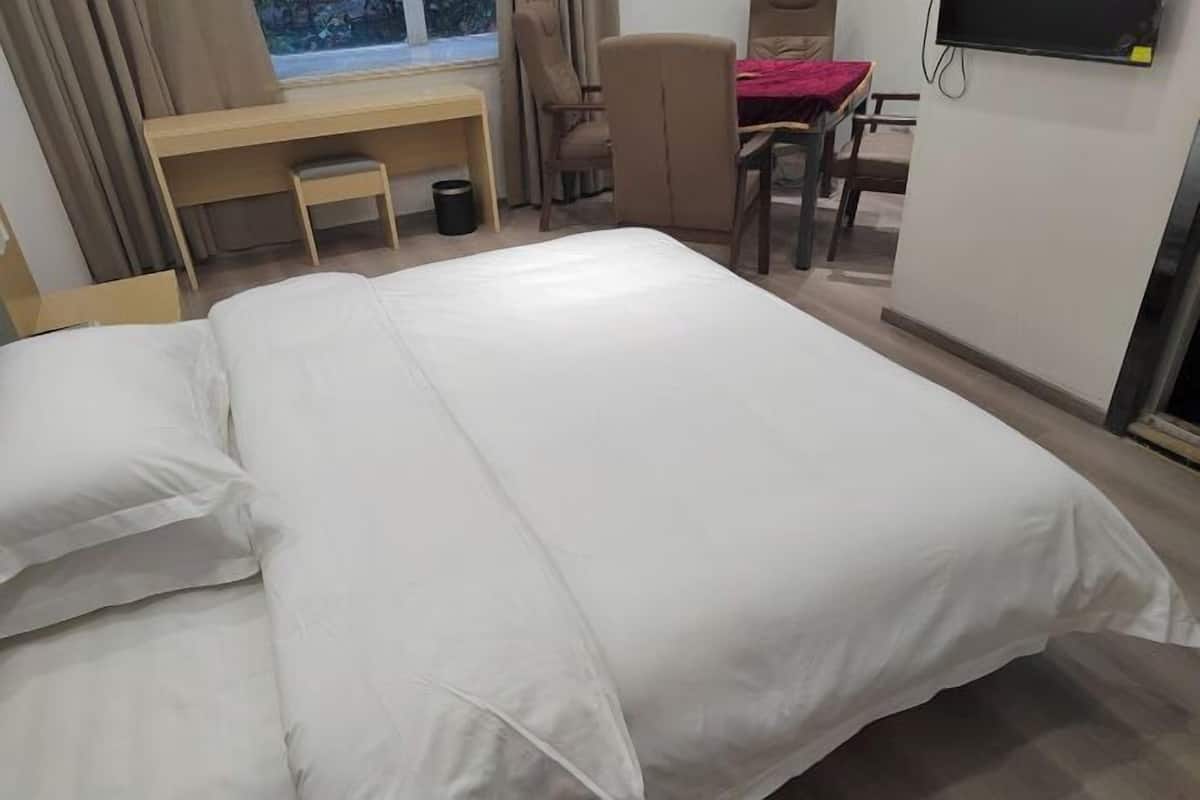 A hotel room with a bed, a desk, a chair, and a TV.