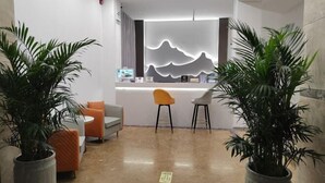 A modern reception area with a desk, chairs, and potted plants. - Xingyue Hotel (Chongqing)