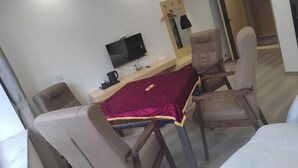 A hotel room with a bed, a desk with a TV, a mirror, and two chairs. - Xingyue Hotel (Chongqing)