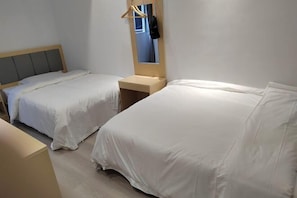 A hotel room with two beds, a bedside table, a mirror, and a hanging coat rack. - Xingyue Hotel (Chongqing)