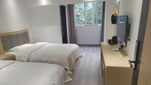 A hotel room with two beds, a desk, a TV, and a window with a view of greenery. - Xingyue Hotel (Chongqing)