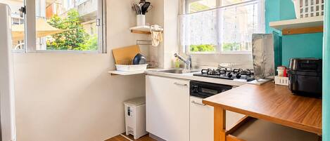 Una cocina compacta con encimera de madera, estufa y lavamanos.