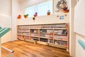 A children's library with wooden shelves filled with books, a window with curtains, and a number sign on the wall. - SimpleStayORIHIME (Ishigaki)