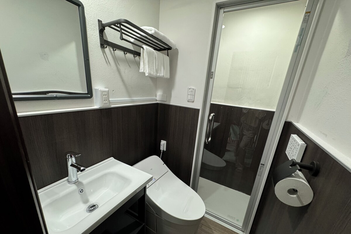 Een moderne badkamer met een wastafel, toilet en douchecabine met glazen wanden.