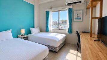 A hotel room with two beds, a desk, a chair, a TV, and a window with curtains.