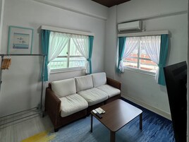 Una habitación con un sofá, una mesita y dos ventanas con cortinas.