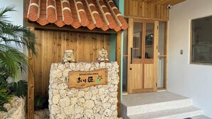 A traditional Japanese-style entrance with a wooden facade, a tiled roof, and a stone wall with a sign reading "ISHIGAKIJIMA". - SimpleStayORIHIME (Ishigaki)