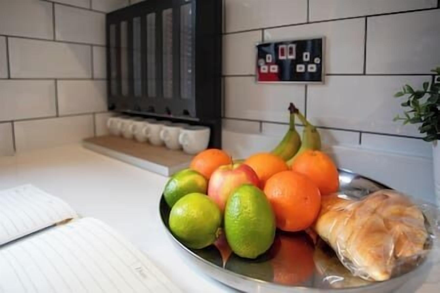 Una encimera de cocina con un frutero que contiene manzanas, naranjas y un plátano.