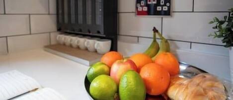 Una encimera de cocina con un frutero que contiene manzanas, naranjas y un plátano.