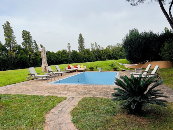 A swimming pool area with lounge chairs and a hammock.