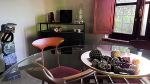 Un espace repas moderne avec une table en verre, une chaise rembourrée de couleur rouge et une assiette décorative ornée de divers objets.