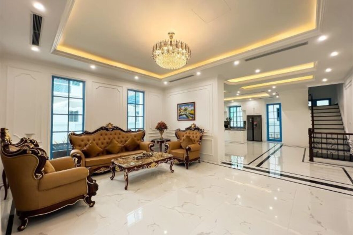 Ein geräumiges Wohnzimmer mit einer Chandelier, zwei Sofas, einem Couchtisch und einer Treppe, die in einen anderen Bereich führt.