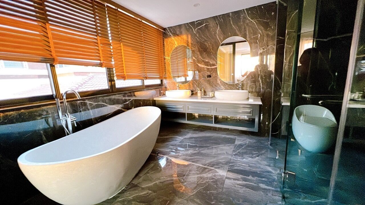 A modern bathroom with a freestanding bathtub, a vanity with a mirror, and a glass-enclosed shower area.