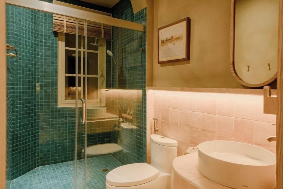 A bathroom with a glass-enclosed shower, a toilet, and two sinks.