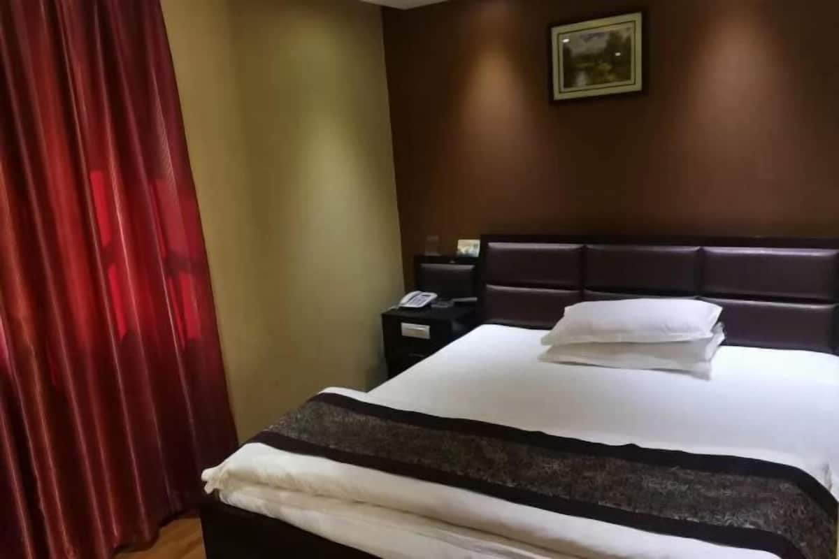 A hotel room with a bed, a nightstand, a telephone, and a painting on the wall.