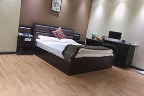 A hotel room with a bed, bedside table, and a desk with a computer. - Luliang Yiyuan Business Hotel (Luliang)