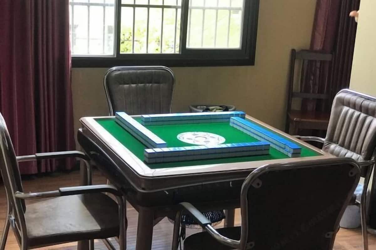 A pool table with a green felt surface, surrounded by four chairs.