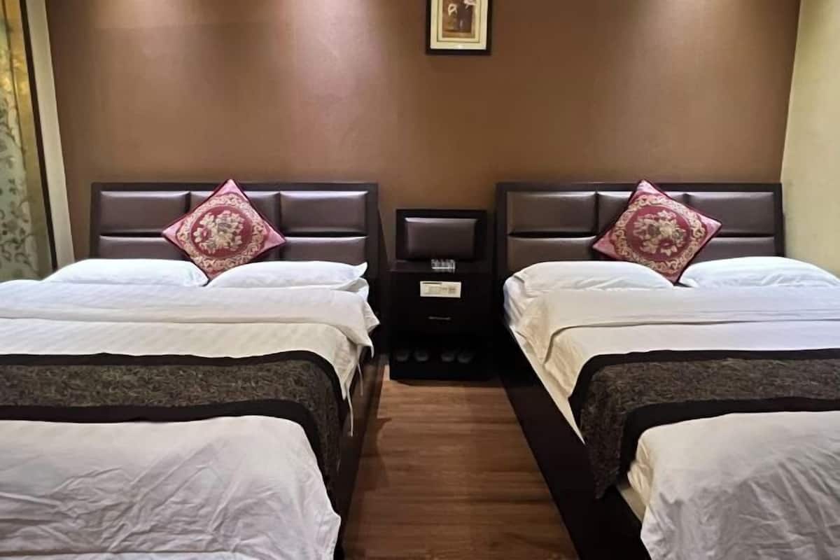 A hotel room with two beds, each with a headboard and a decorative pillow.