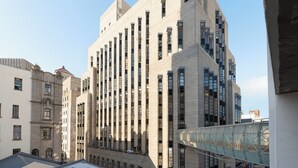 Un edificio moderno de gran altura con un diseño de esquina llamativo, con varios pisos y ventanas amplias.