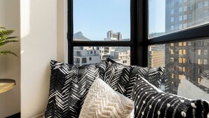 Una ventana con vista a un paisaje urbano, que incluye edificios y una montaña.